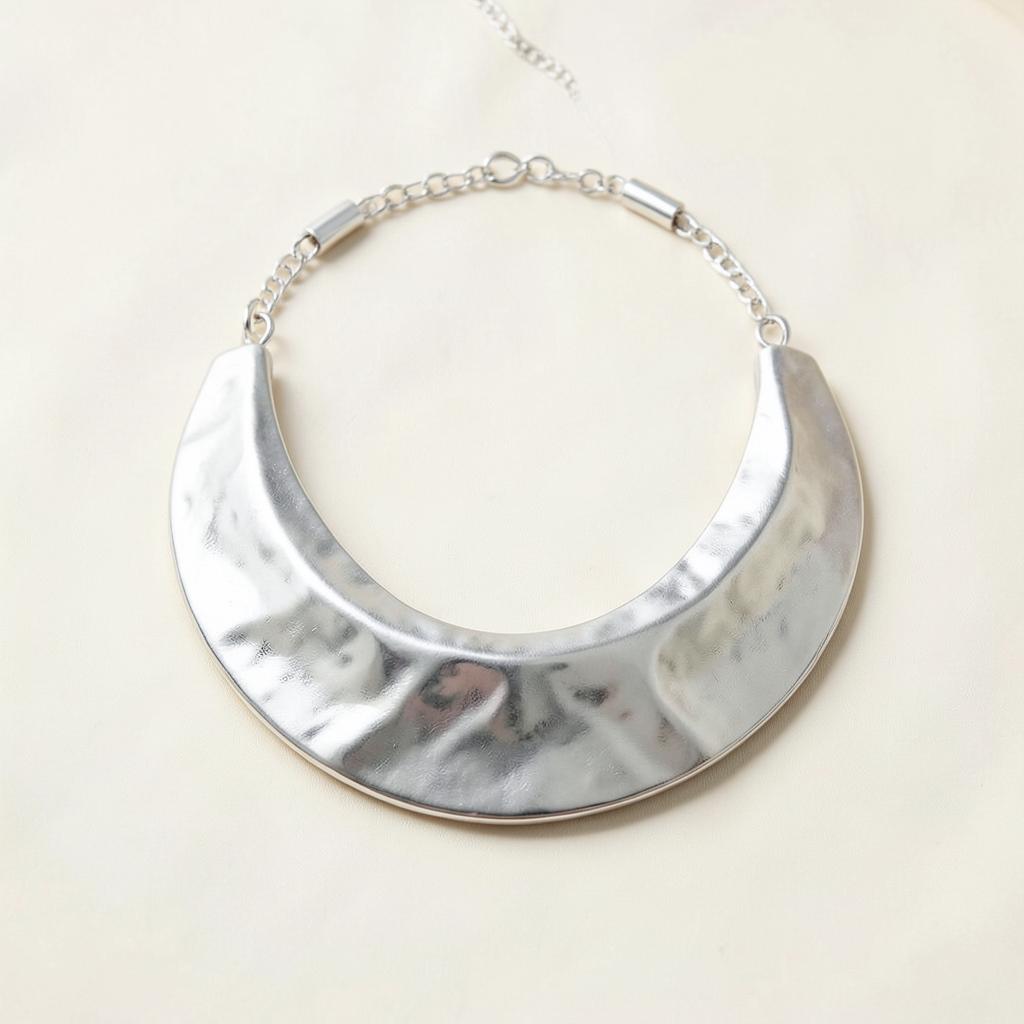 Ilargi crescent silver necklace with a curved polished form on an ivory background